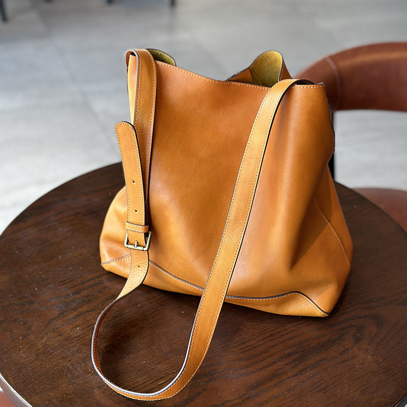 Brown leather handbag on a wooden surface with a blurred background