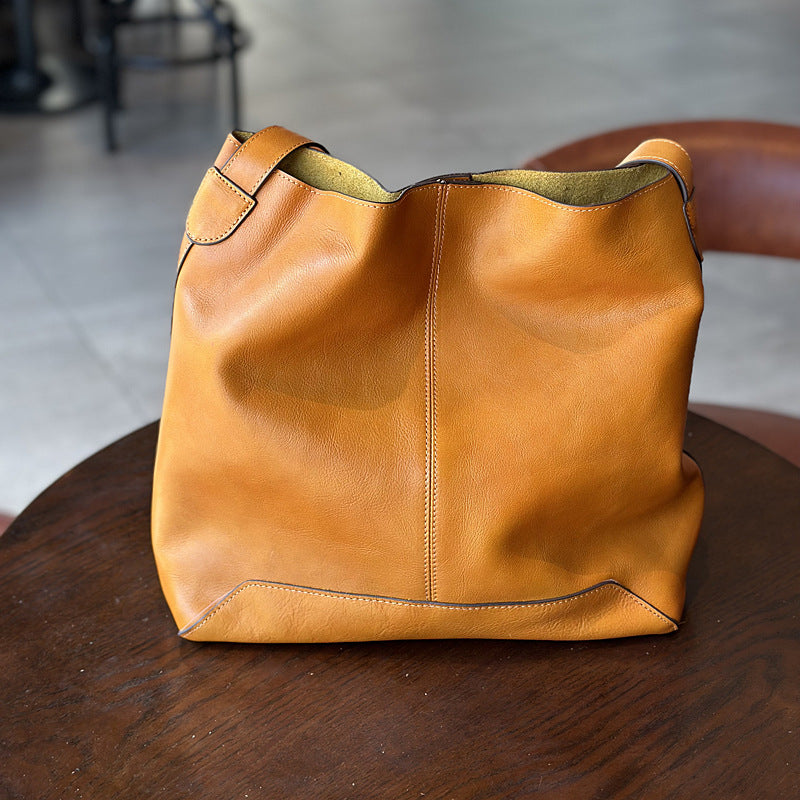 Brown leather shoulder bag on a wooden surface with a blurred background