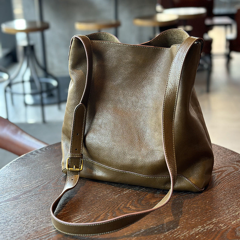 Dark green leather bag on a wooden table with a blurred cafe background