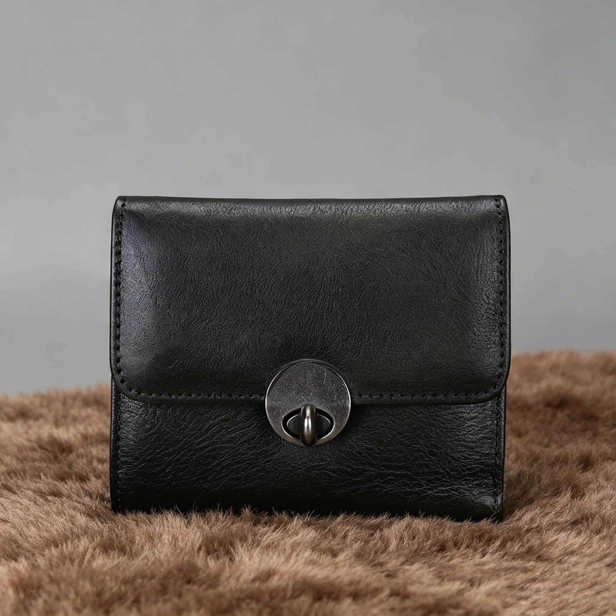 Black leather wallet with a silver clasp on a brown surface with a gray background