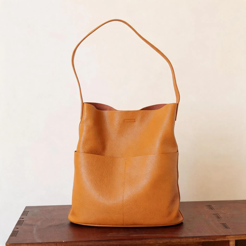 Brown leather bag on a wooden surface with a plain background