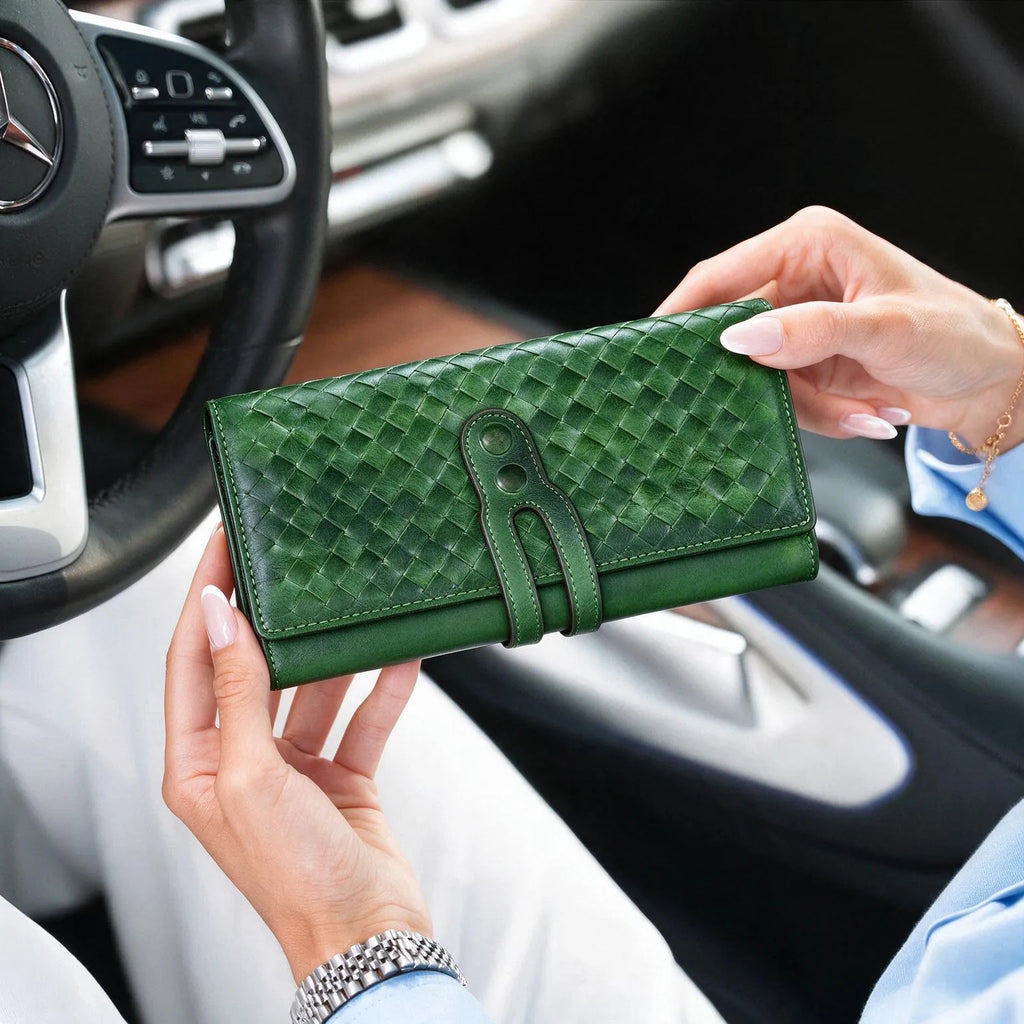 Woman hands holding green woven leather long wallet inside luxury car, lifestyle product shot of handmade leather clutch