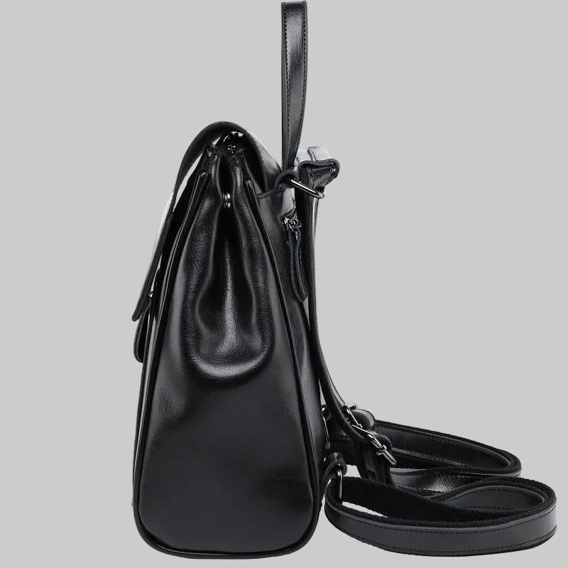Black leather handbag with a shoulder strap on a light gray background