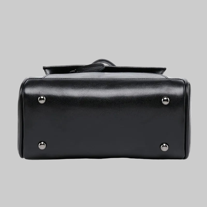 Black handbag with silver studs on a gray background