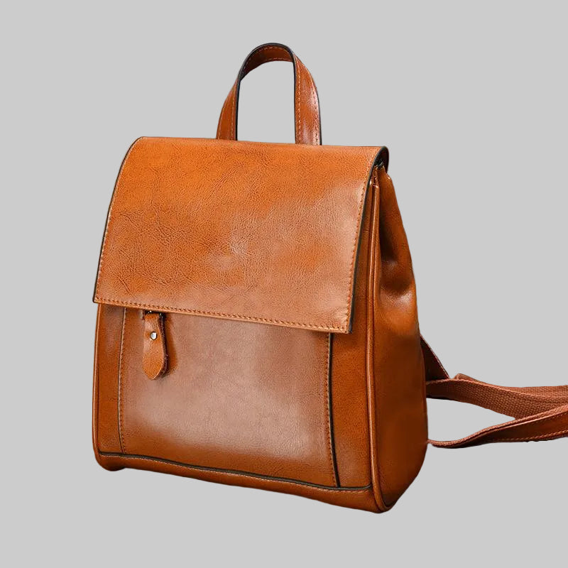 Brown leather backpack on a vintage suitcase with a rustic background