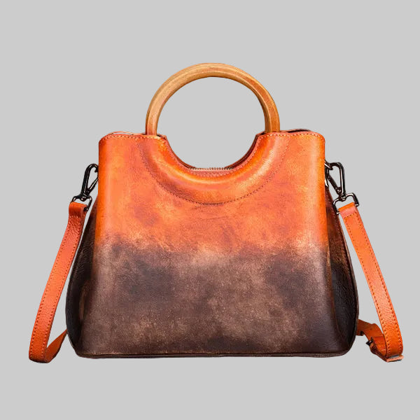 Brown leather handbag with wooden handle on a gray background