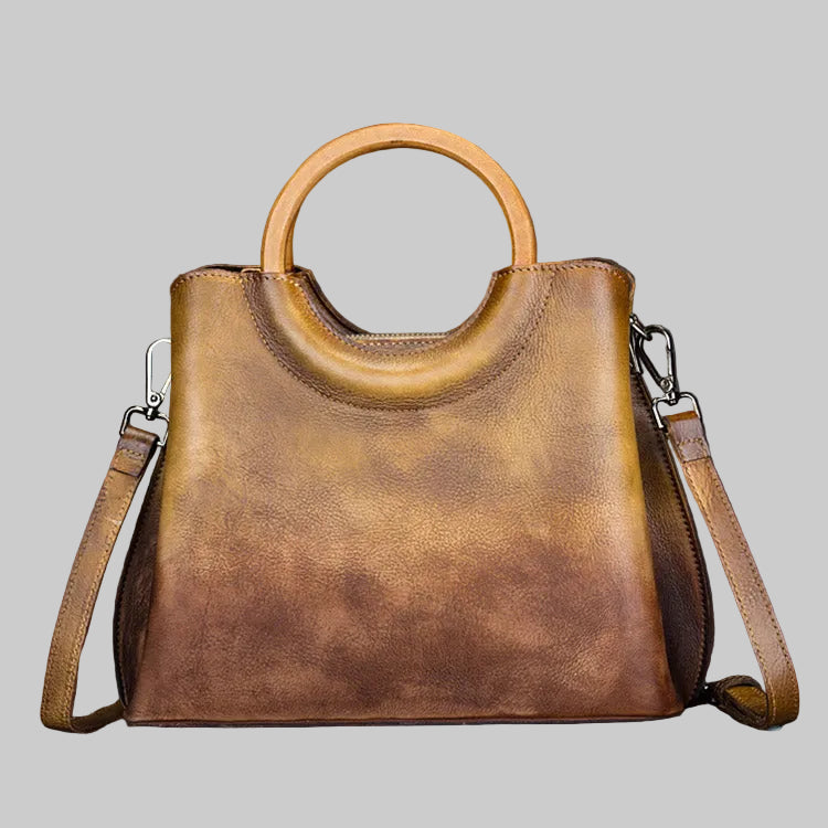 Brown leather handbag with a handle on a gray background