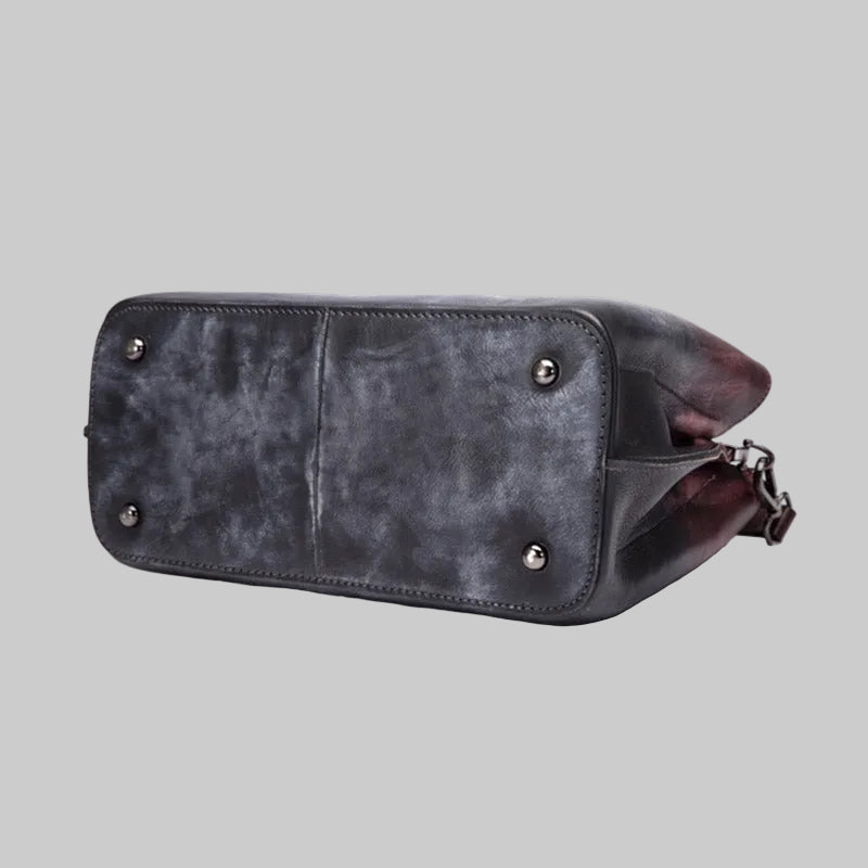 Gray leather bag with studded details on a light gray background