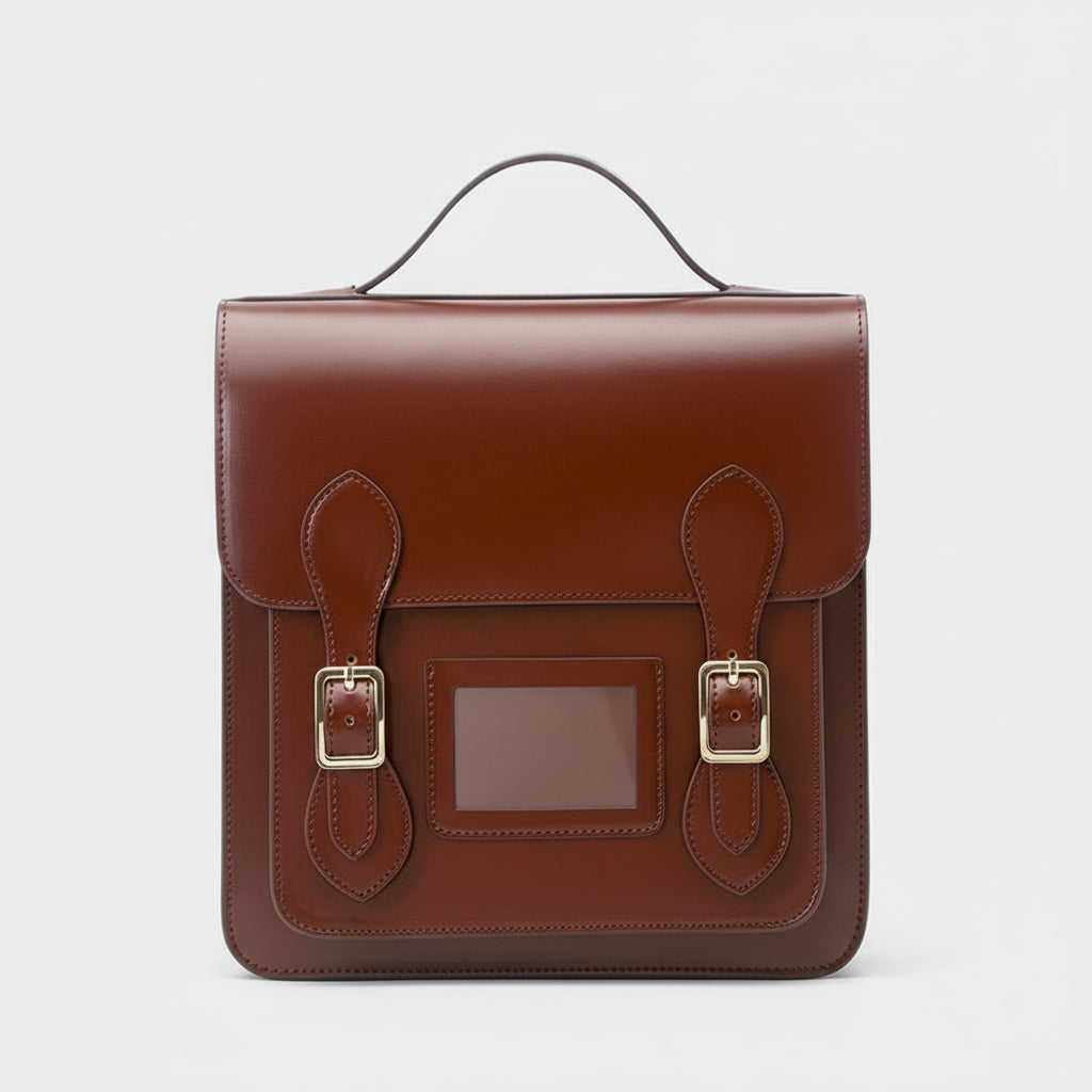 Brown leather satchel with gold buckles on a light gray background